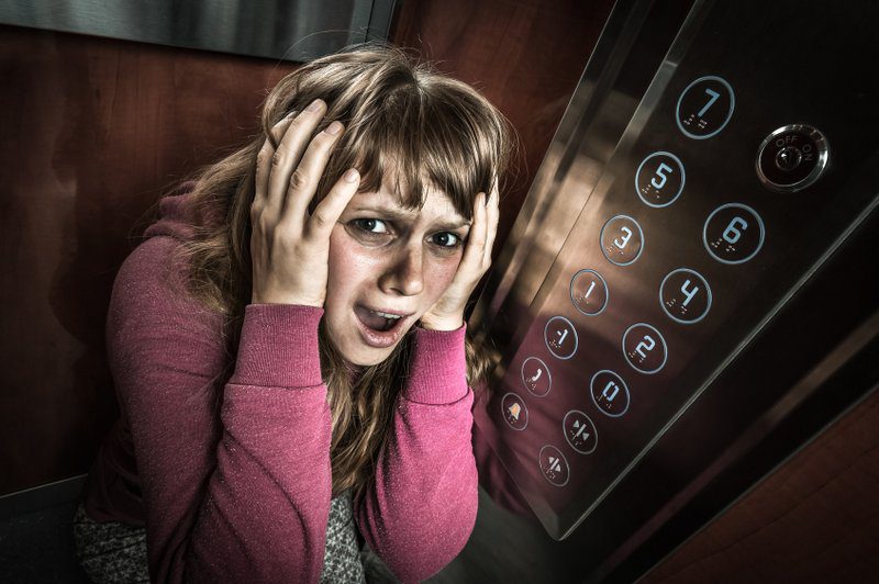 Panikattacken Symptome können Betroffene gefühlt um den Verstand bringen; hier eine Frau mit Klaustrophobie in einem Aufzug (© andriano_cz / Fotolia)
